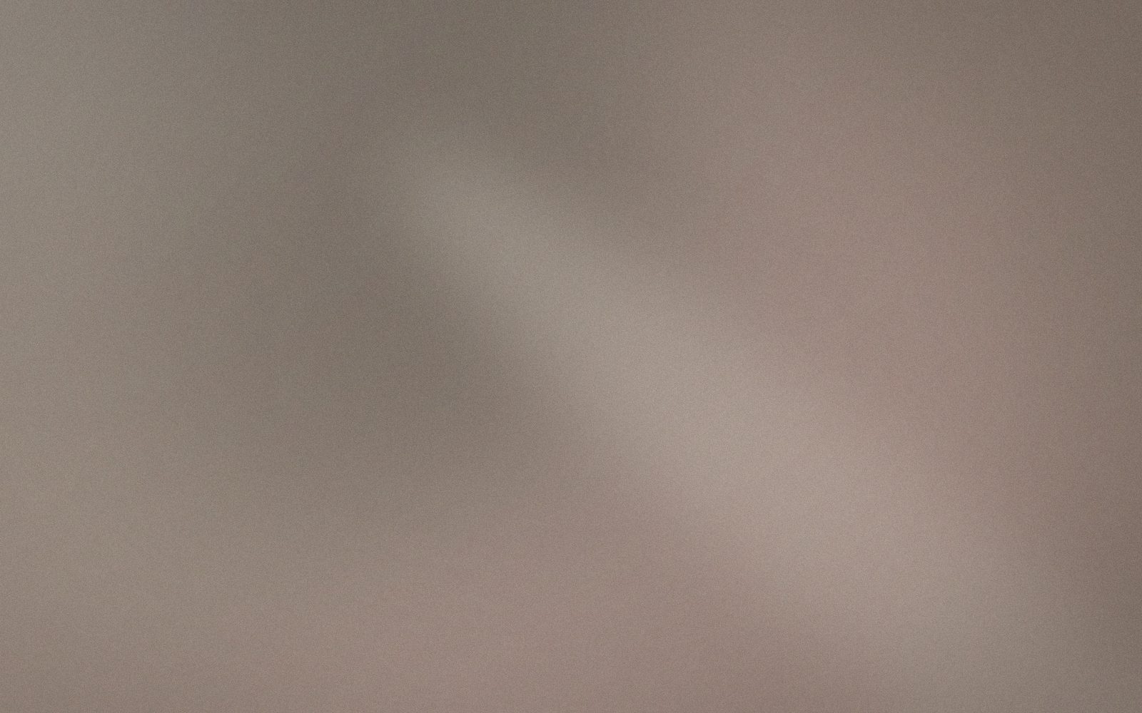 Interno del salone in controluce mattutino: lino avorio, pietra chiara e una mano che sfiora un asciugamano piegato