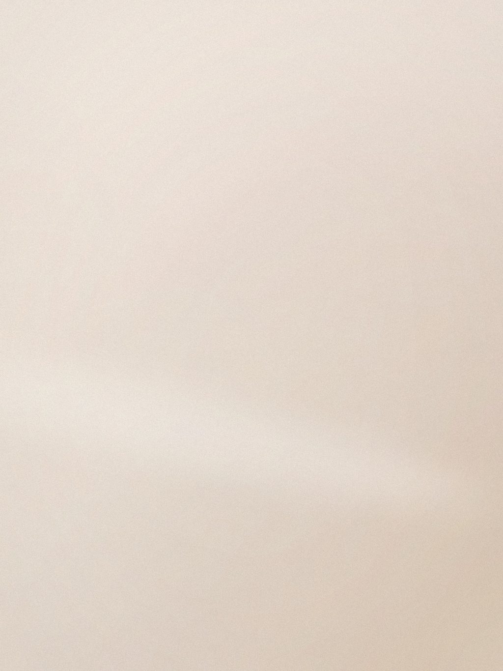 Mani con manicure nude appoggiate su una superficie in pietra chiara, luce laterale morbida