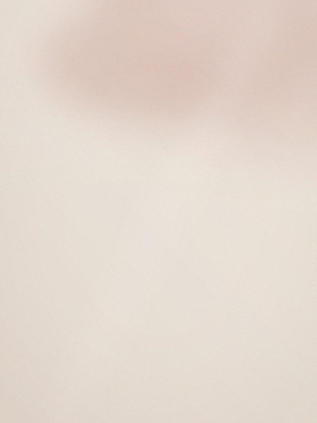 Mani dell'operatrice che applicano una maschera in crema sul viso, dettaglio parziale
